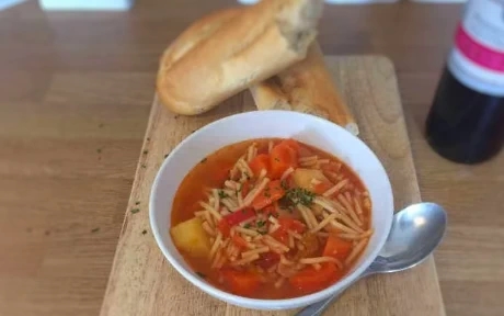 bowl of minestrone soup with french loaf and red wine